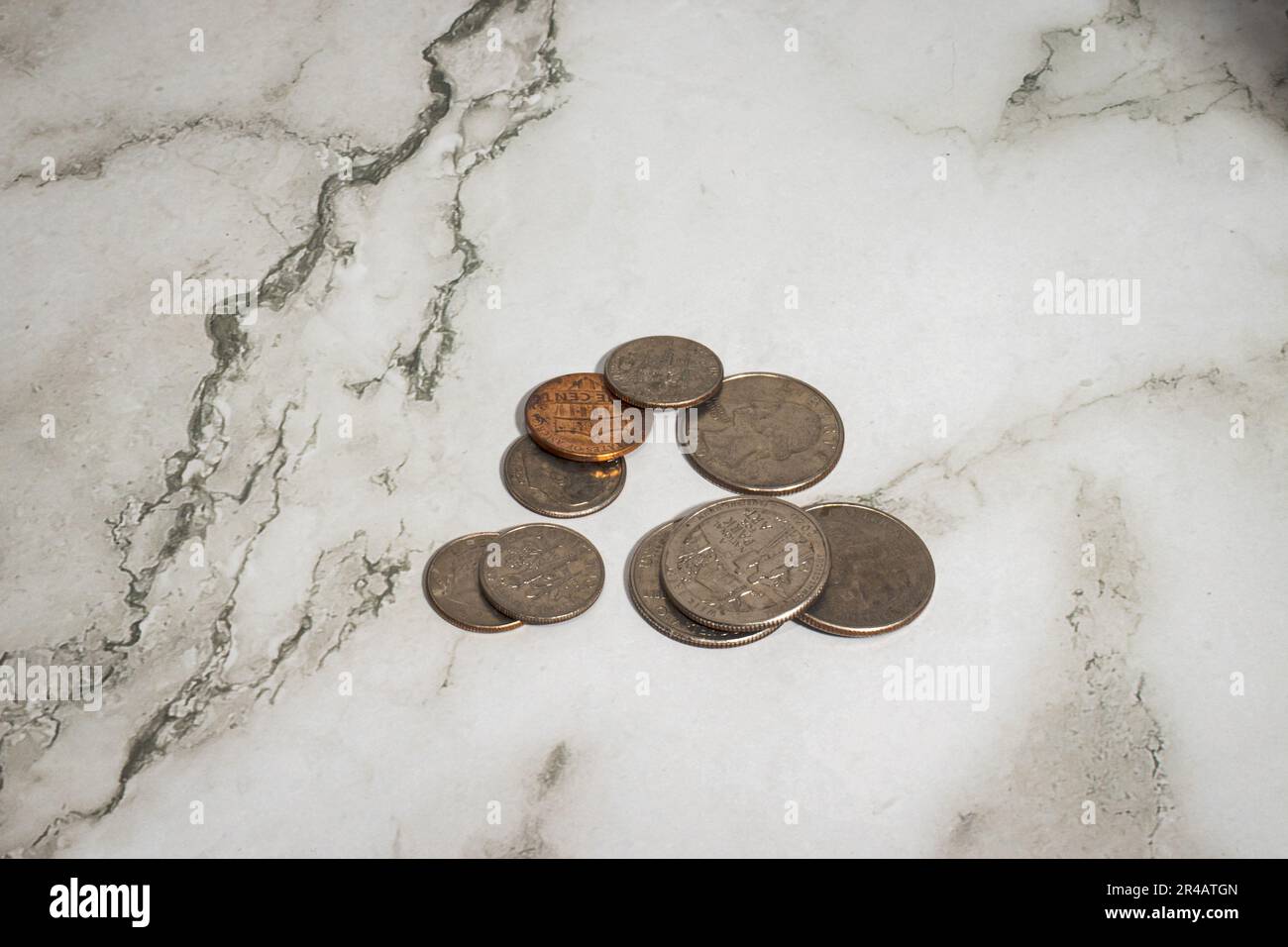 A pile of several coins sitting atop a marble countertop Stock Photo