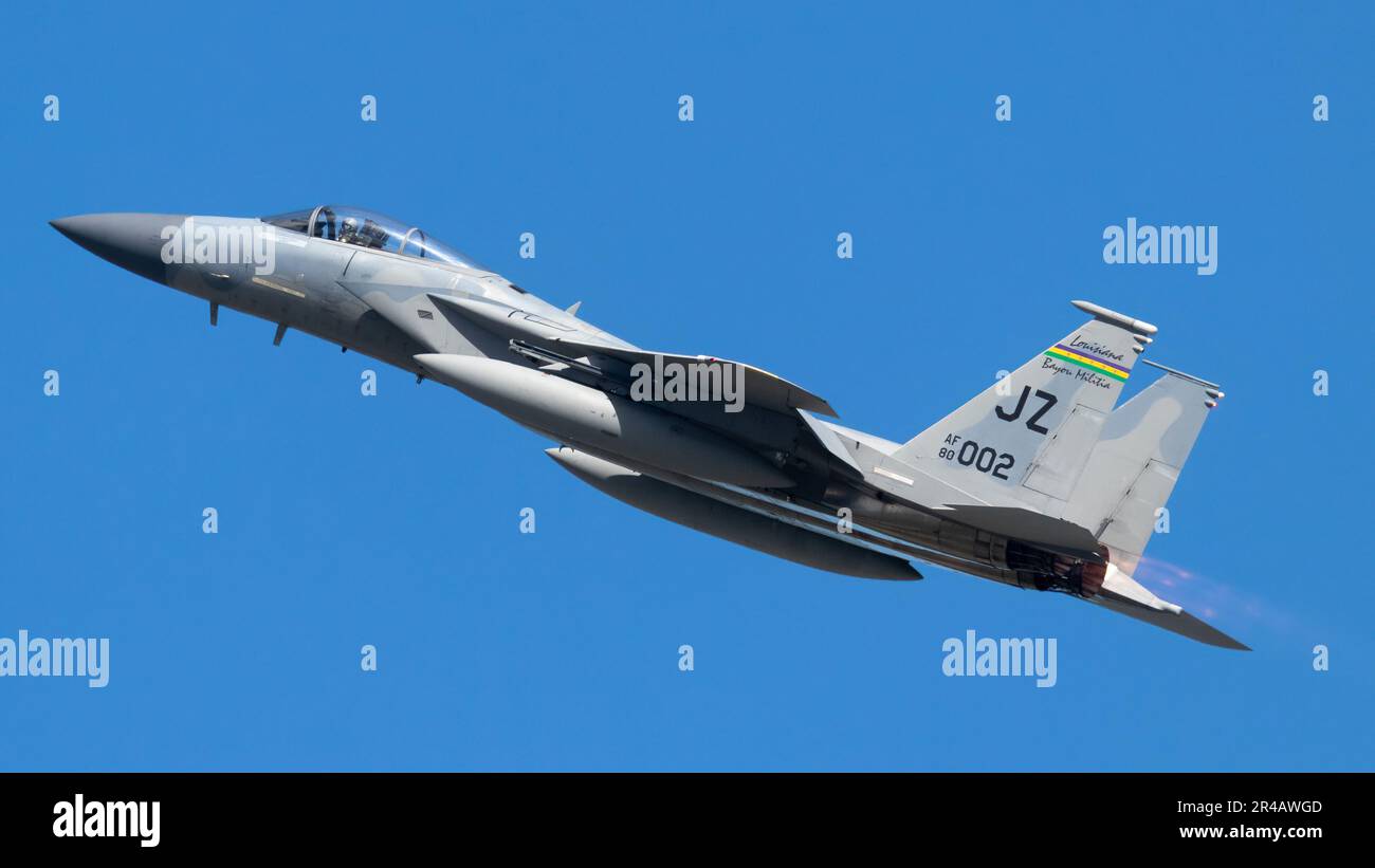 A fighter jet soars through the sky, leaving a trail of vapor in its