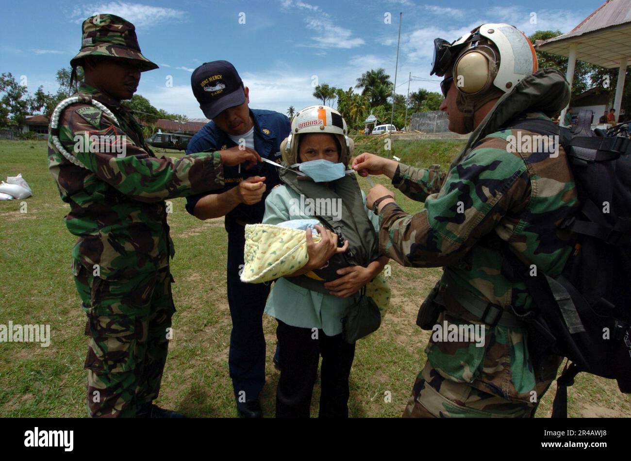 US Navy  Lt.j.g. right, Chief Hospital Corpsman center, and an Indonesian military member assist an Indonesian woman in preparation for a medical evacuation. Stock Photo