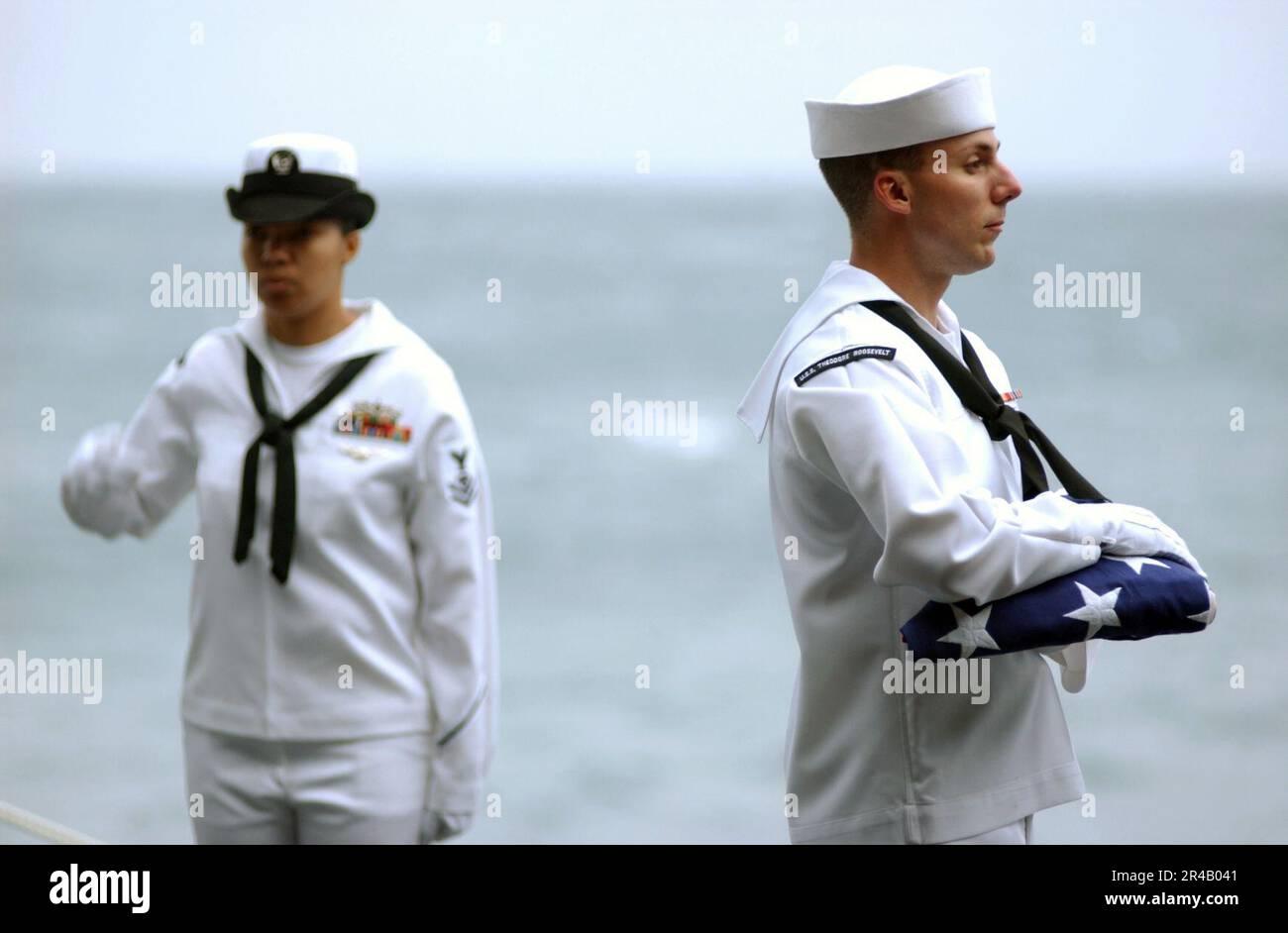 US Navy Airman holds the national ensign before passing it over to the commanding officer of the