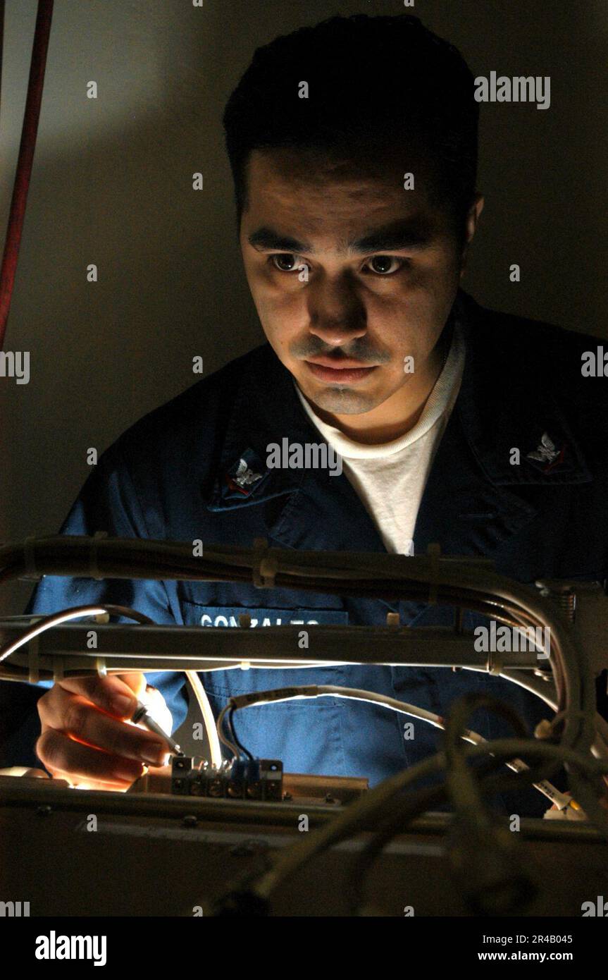 US Navy Electronics Technician 3rd Class checks the wiring of a High