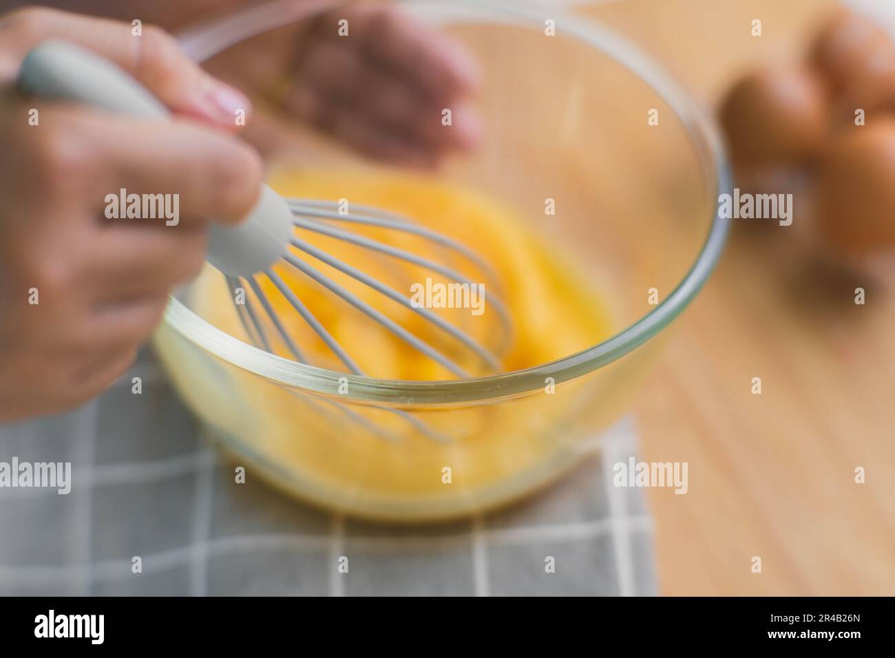 https://c8.alamy.com/comp/2R4B26N/young-woman-cooking-in-bright-kitchen-hands-whisking-eggs-in-a-bowl-placed-on-towel-and-wooden-table-preparing-ingredients-for-healthy-cooking-home-2R4B26N.jpg