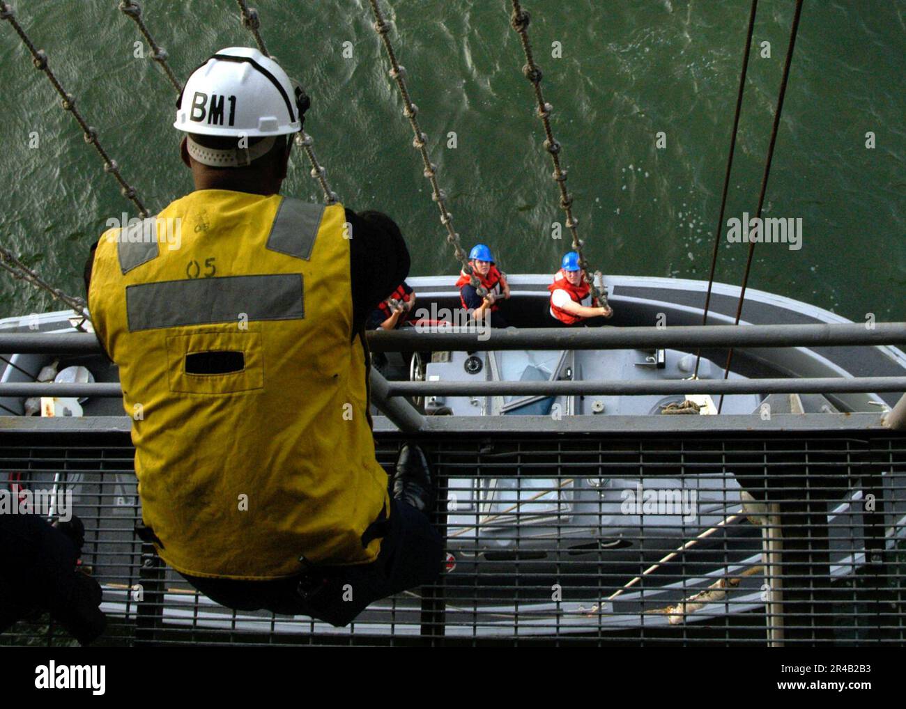 US Navy Boatswain's Mate 1st Class directs the lowering of the Captain