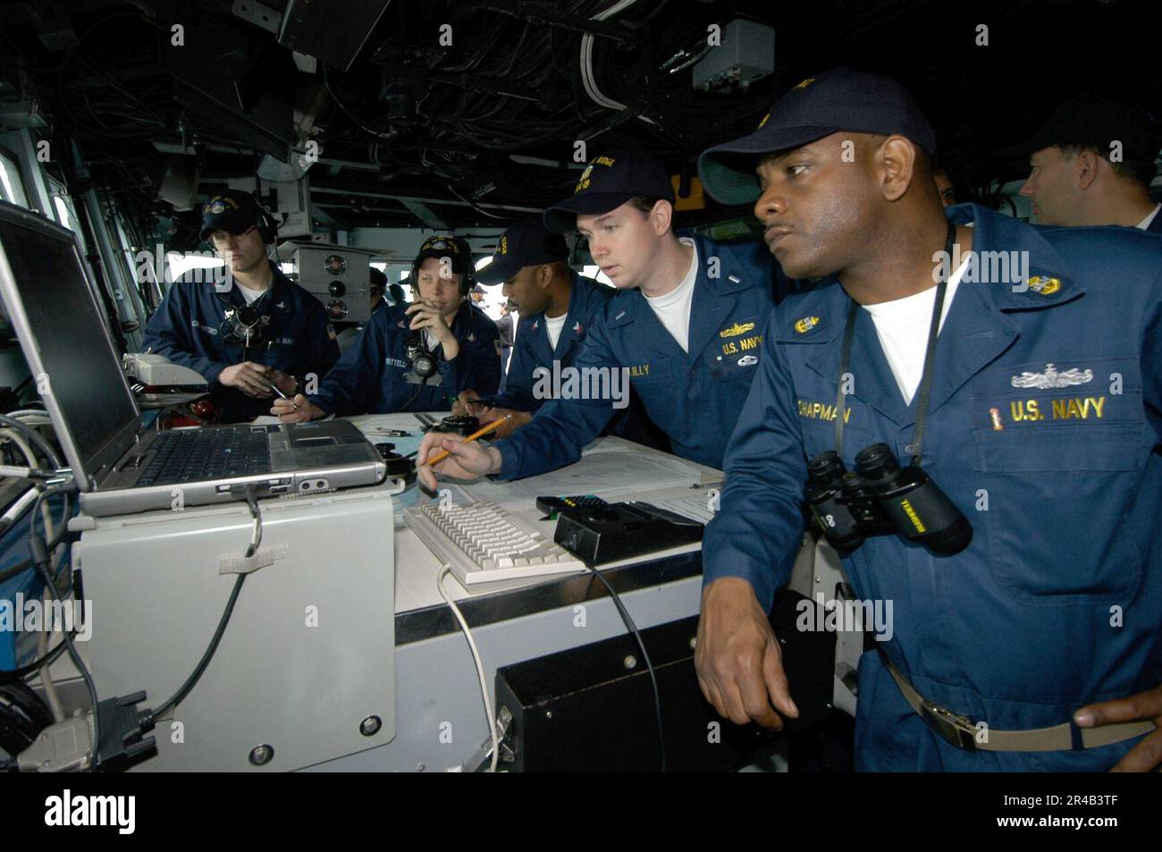 US Navy  Lt. j.g. center, plots a course as the 7th Fleet amphibious command ship USS Blue Ridge (LCC 19) departs Brisbane, Australia. Stock Photo