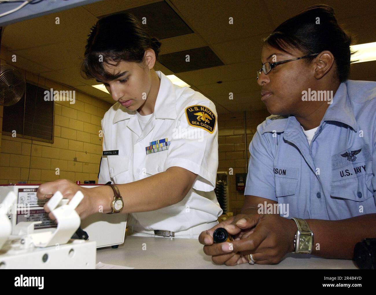 US Navy Photographer's Mate 1st Class Aviation Warfare right, instructs U.S. Naval Sea Cadet Seaman as she learns the basics of developing photographic film Stock Photo