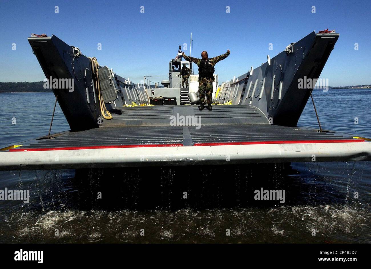 US Navy A Boatswain's Mate signals to raise the ramp on a landing craft ...