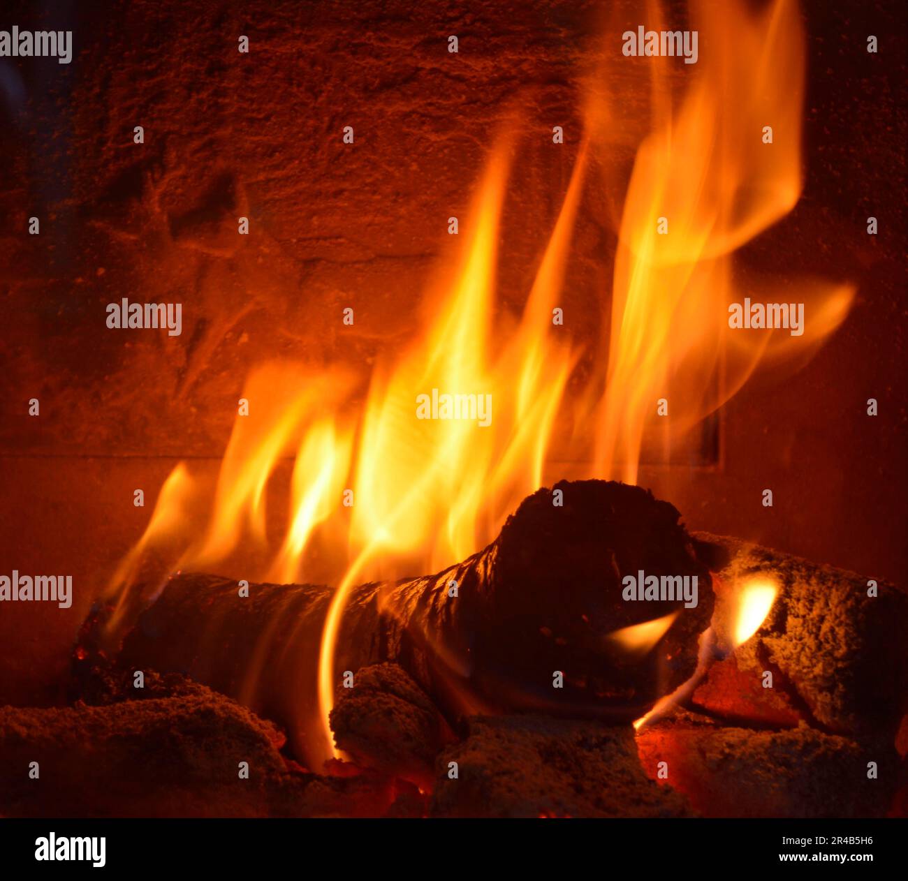 Heating in the heating fireplace with round wood briquettes Stock Photo