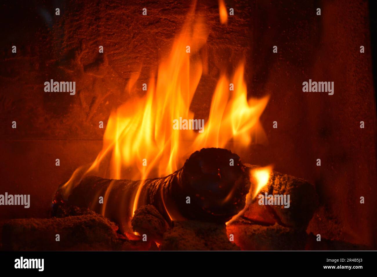 Heating in the heating fireplace with round wood briquettes Stock Photo