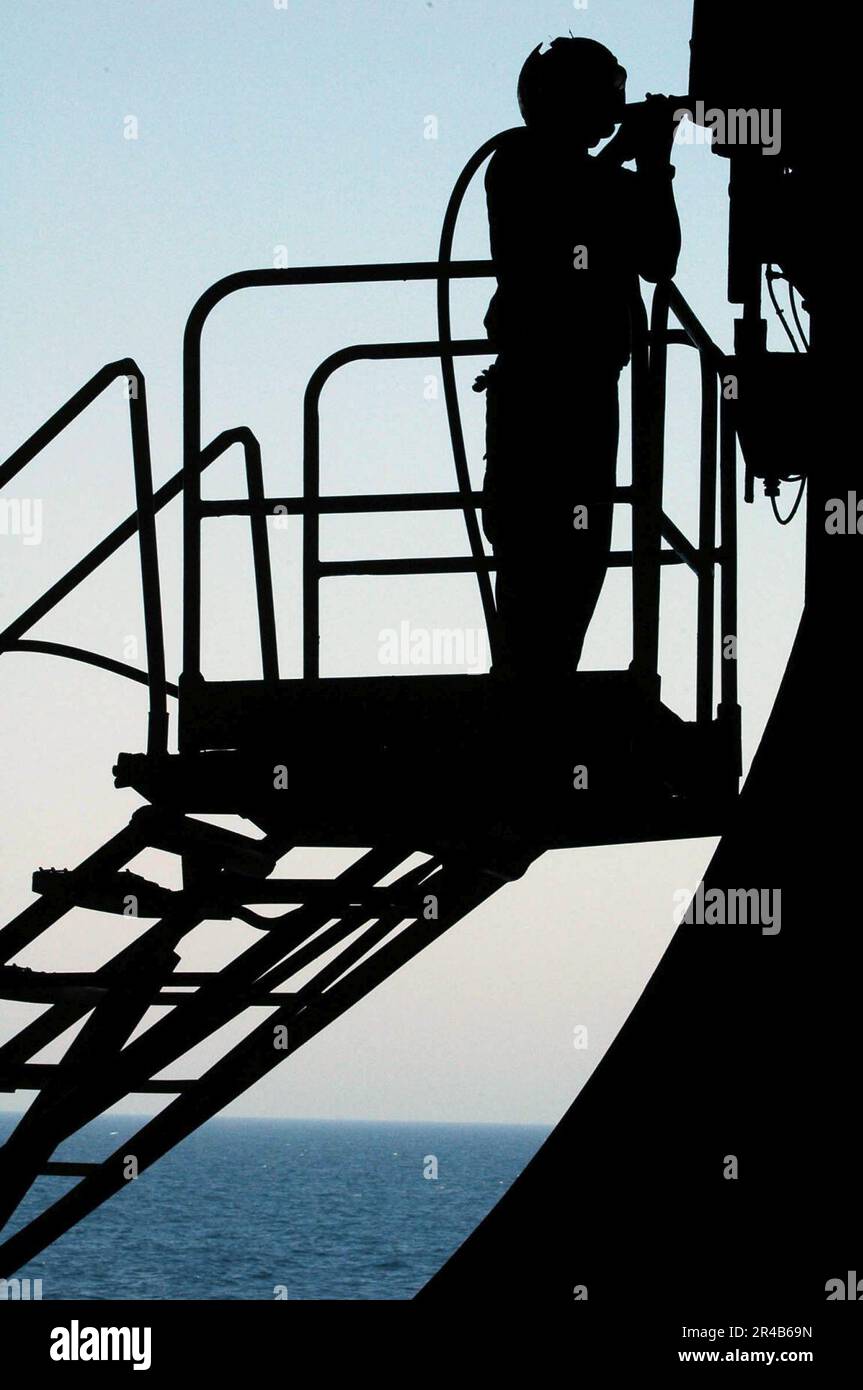 US Navy Airman uses a needle gun to remove paint from an elevator door