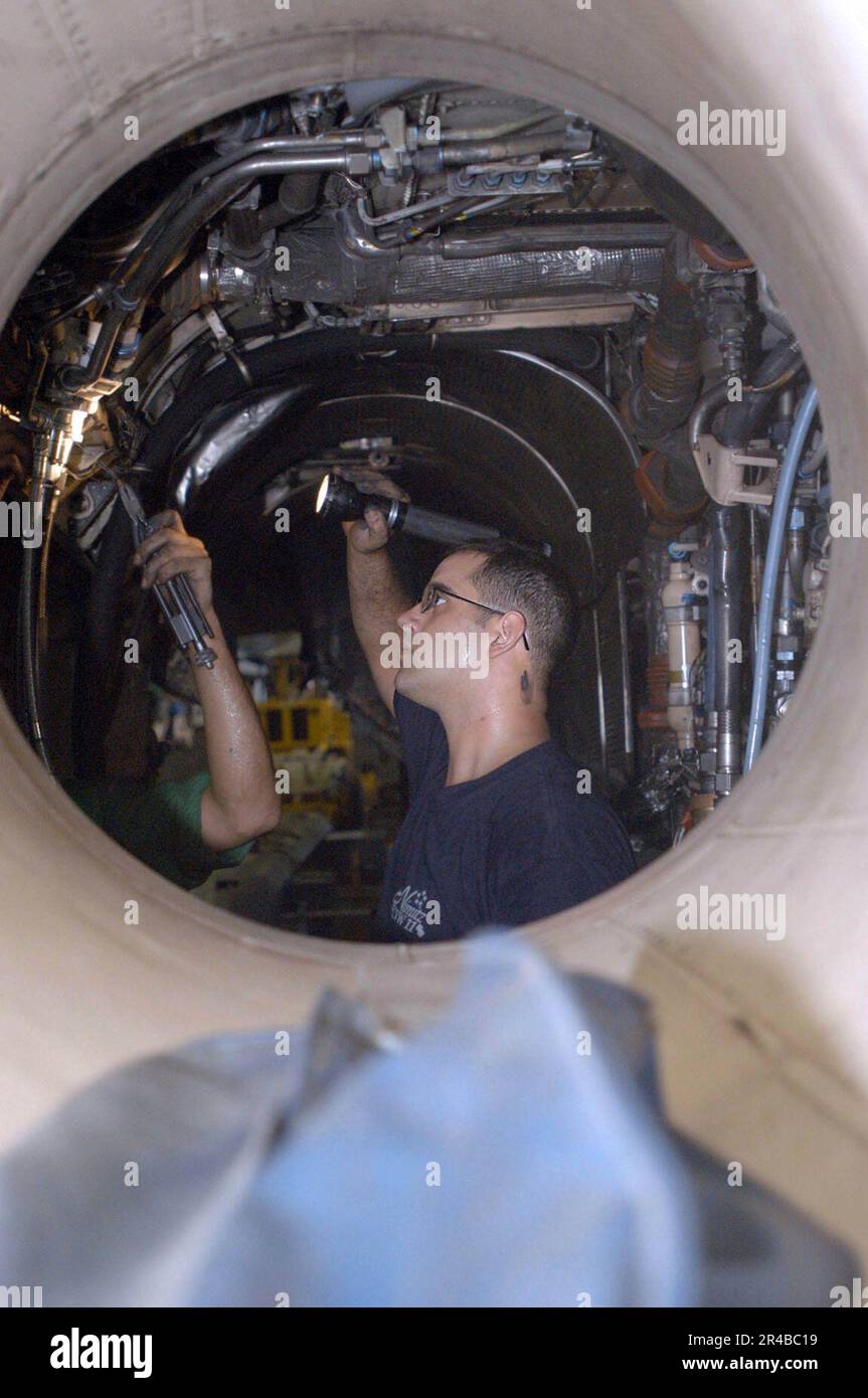 US Navy Aviation Structural Mechanic 2nd Class repairs fuel lines in the engine compartment of