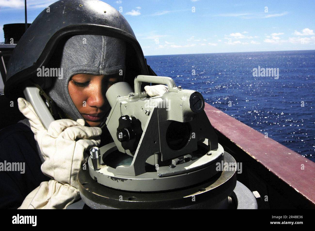 US Navy  Seaman keeps a watchful eye out as portside lookout by searching for surface contacts through a telescopic alidade. Stock Photo