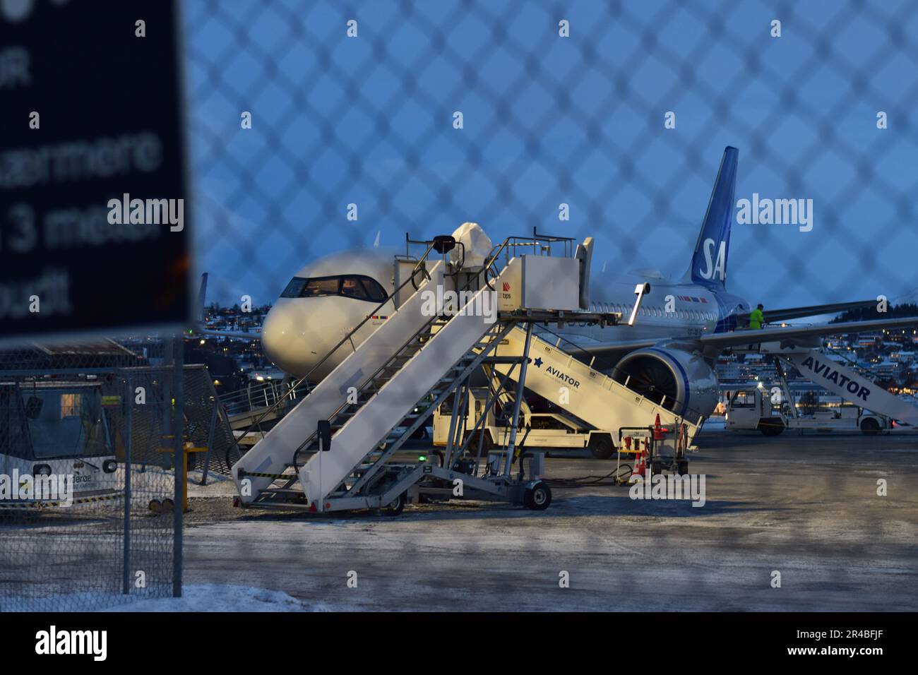 A white commercial aircraft is parked on a tarmac runway at an airport terminal Stock Photo