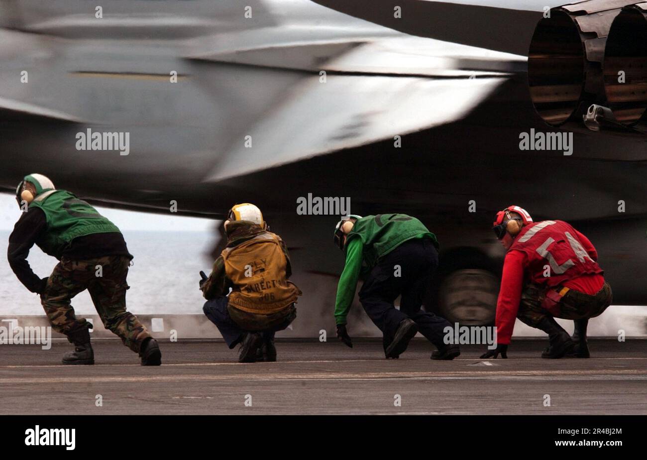 US Navy Flight deck personnel duck under the exhaust of an F-A-18 ...