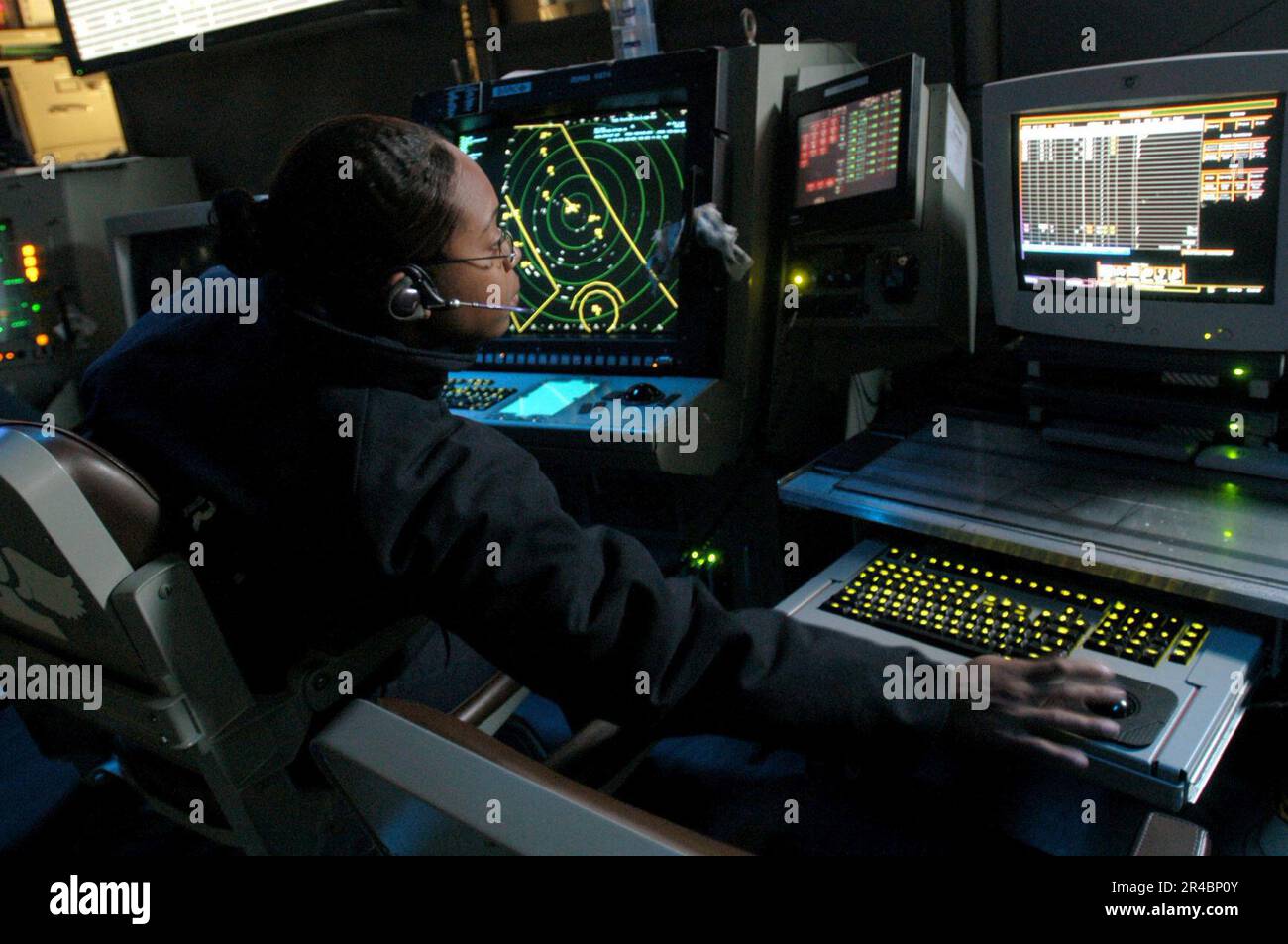 US Navy  Air Traffic Controller 2nd Class Petty Officer monitors both the Approach A and Approach ISIS consoles in the Carrier Air Traffic Control Center (CATCC) aboard USS Theodo. Stock Photo