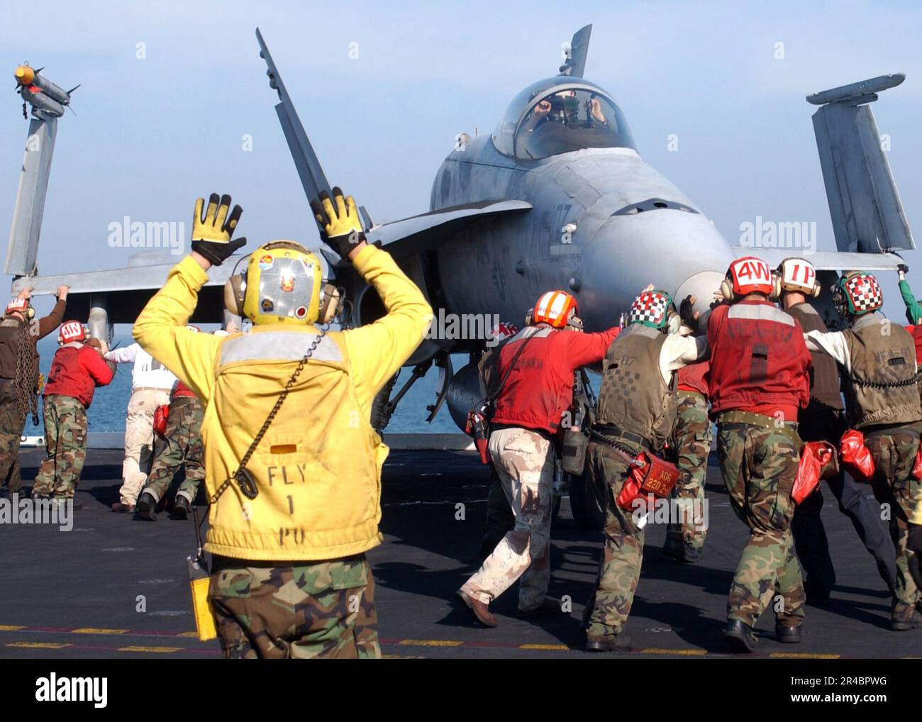 US Navy Squadron personnel work together to push back an FA18C