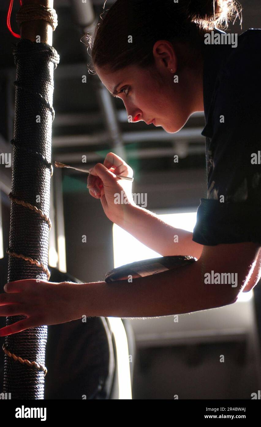 US Navy Seaman Recruit assigned to Deck Department paints a stanchion ...