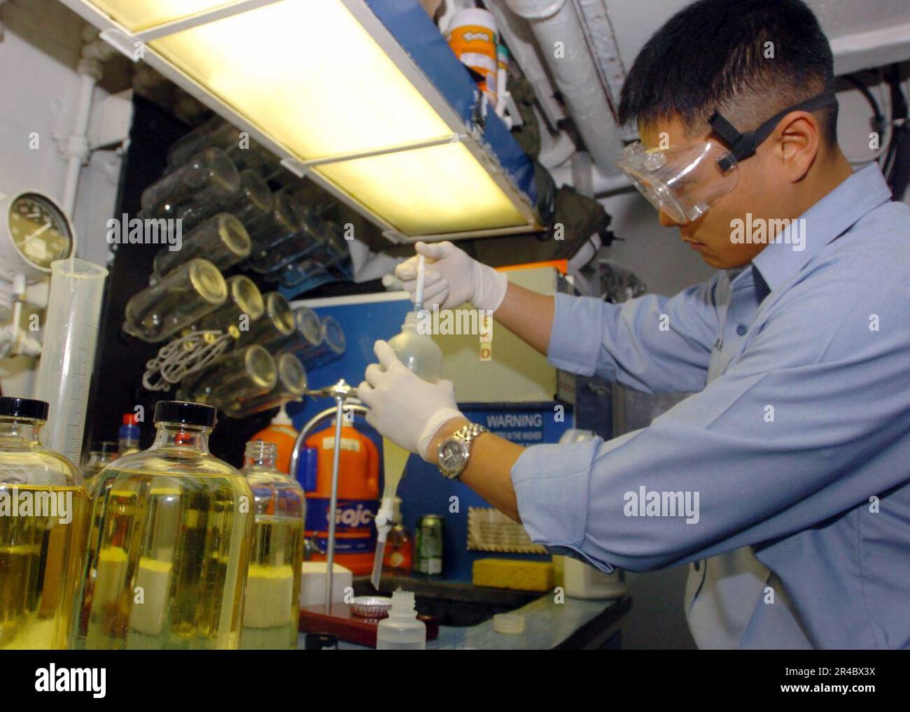 US Navy Airman adds water to a sample of JP5 fuel while performing a