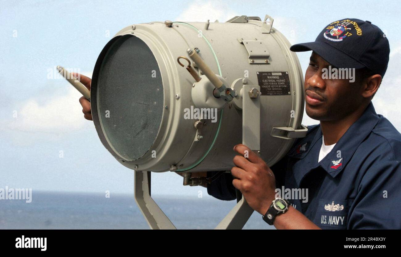 US Navy Quartermaster 2nd Class sends a flashing light signal to the guided missile destroyer