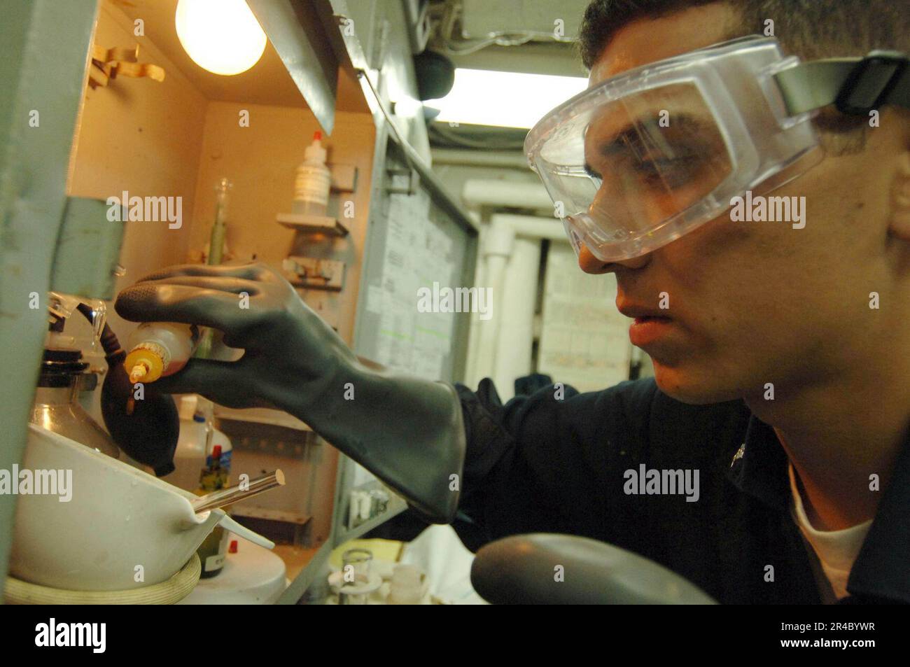 US Navy Engineman 3rd Class adds drops of chloride reagent into a