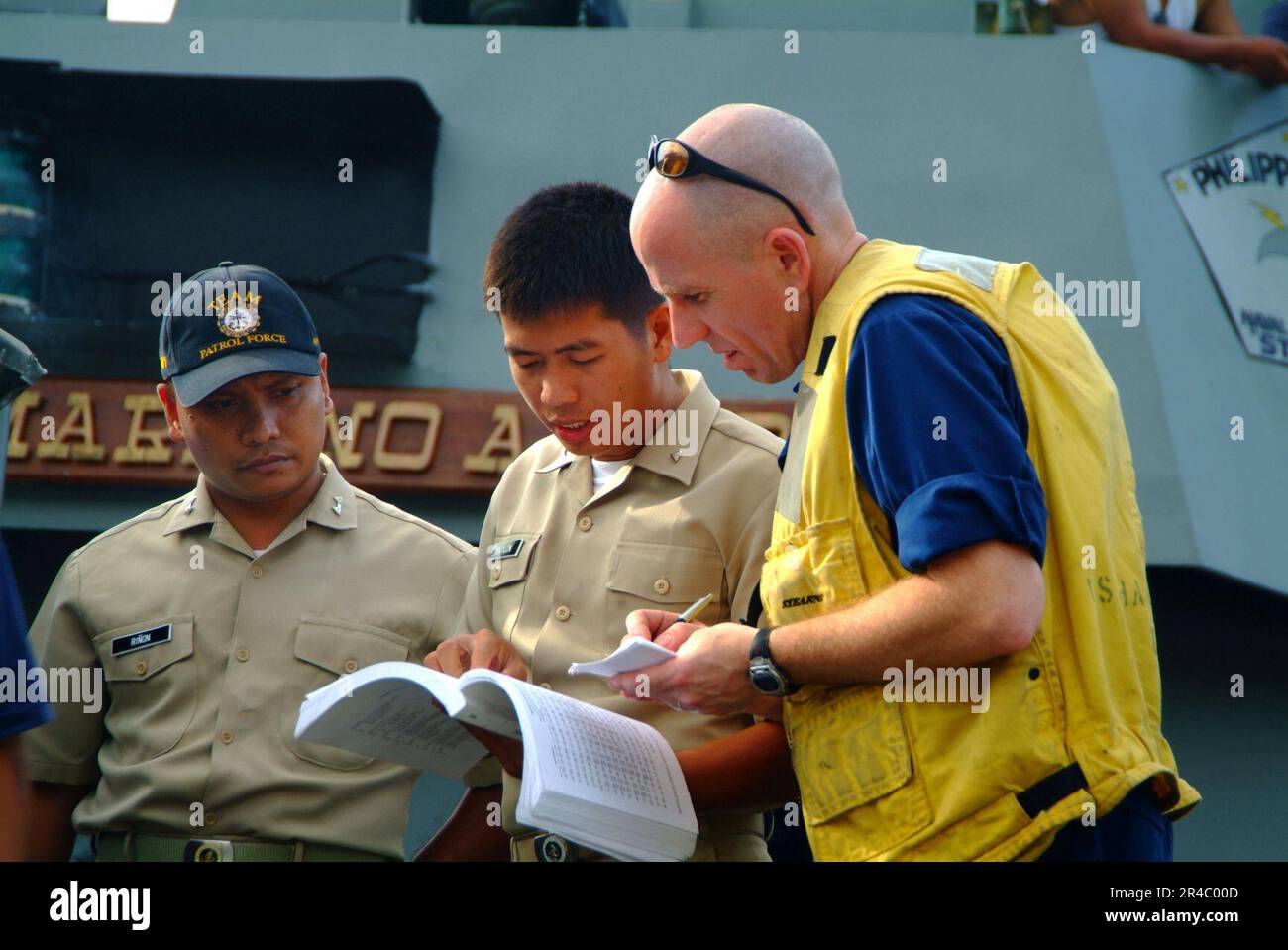 US Navy  Chief Warrant Officer coordinates information with Philippine Naval personnel while conducting a beach survey. Stock Photo