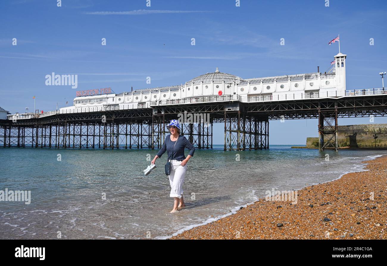 Brighton UK 27th May 2023 - The water is a bit chilly for this lady as she paddles  on Brighton beach by the pier as visitors enjoy the bank holiday weekend sunshine which is forecast for most of the UK over the next few days : Credit Simon Dack / Alamy Live News Stock Photo