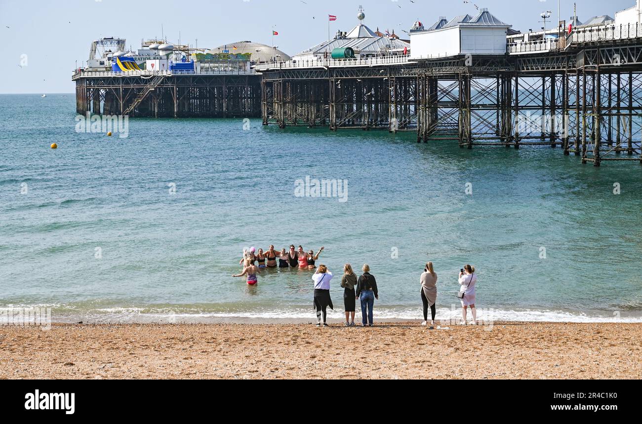 Brighton UK 27th May 2023 - Swimmers enjoy a dip  on Brighton beach by Brighton Palace Pier as visitors enjoy the bank holiday weekend sunshine which is forecast for most of the UK over the next few days : Credit Simon Dack / Alamy Live News Stock Photo