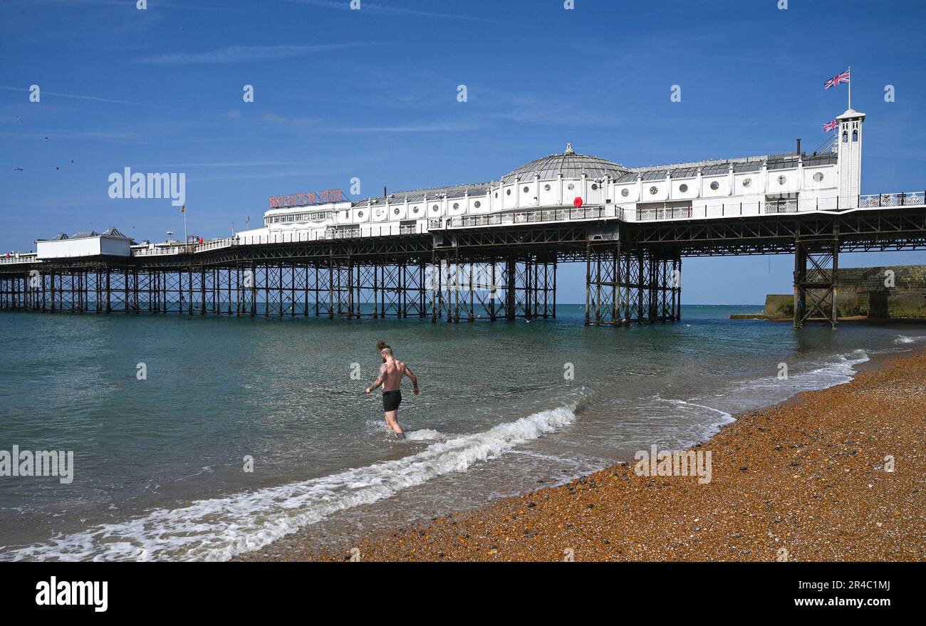 Brighton UK 27th May 2023 - A swimmer heads into the sea in Brighton as visitors enjoy the bank holiday weekend sunshine which is forecast for most of the UK over the next few days : Credit Simon Dack / Alamy Live News Stock Photo