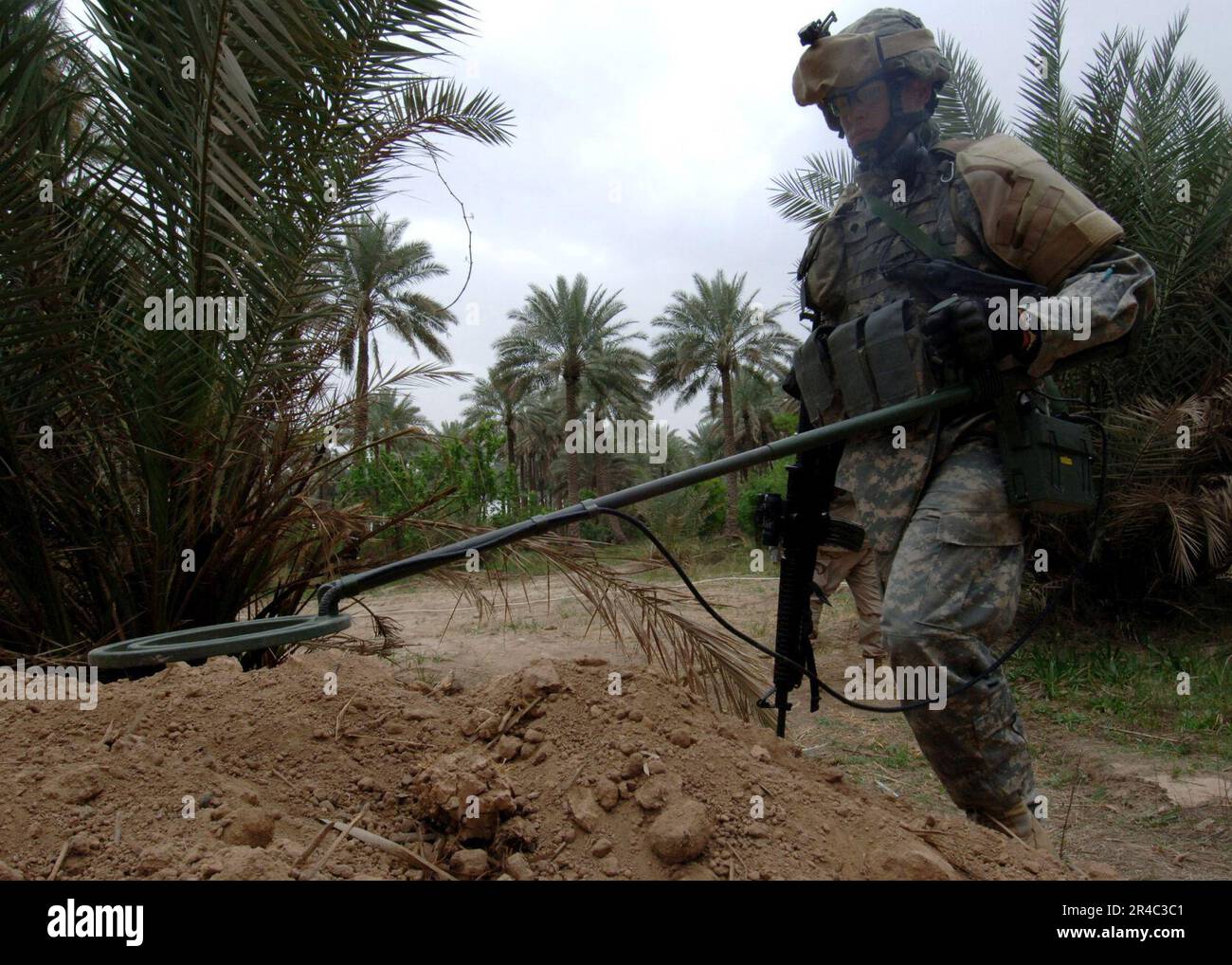 US Navy  U.S. Army Spc. uses a metal detector to search for hidden weapons caches in Tarmiya, Iraq during counter-insurgency operations to rid the town of insurgents. Stock Photo