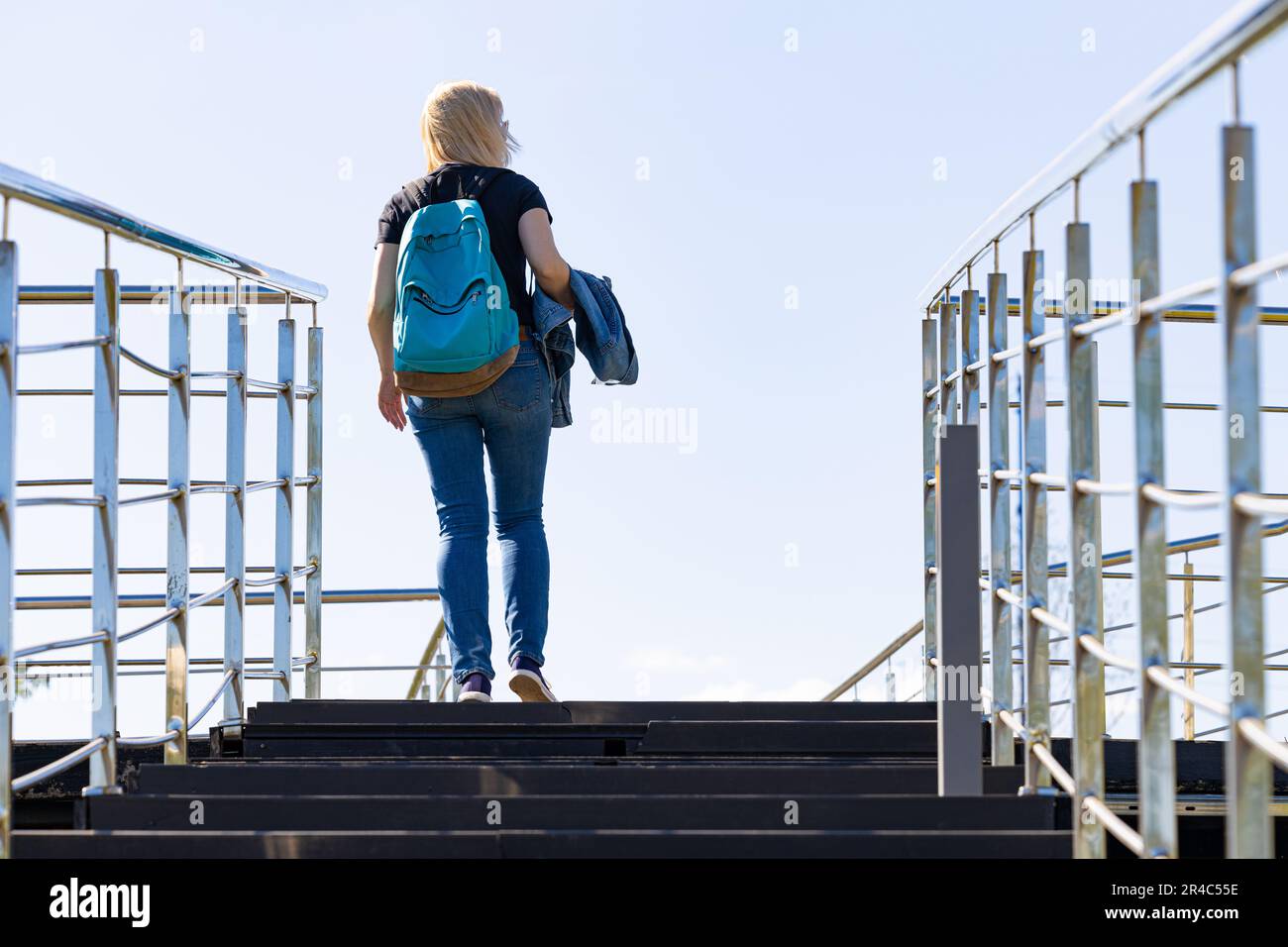 a girl with a backpack climbs the stairs. woman standing at the top of