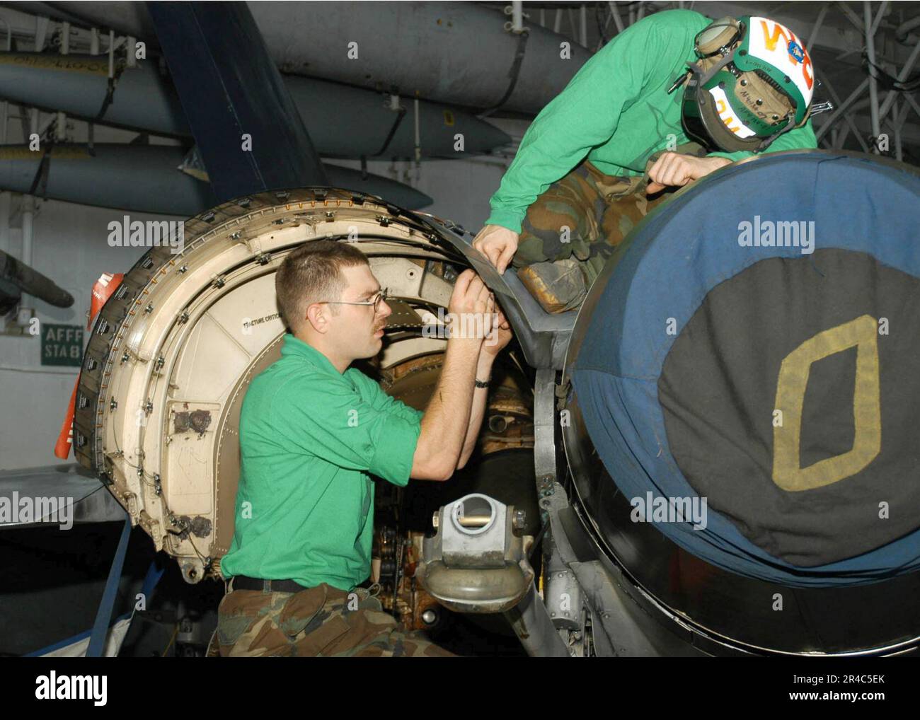 US Navy  Aviation Structural Mechanic Airman left, and a fellow Sailor perform routine phase maintenance on an F-A-18C Super Hornet. Stock Photo