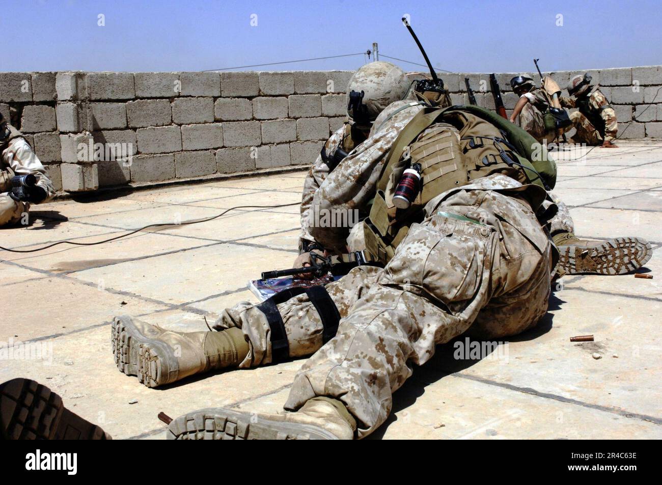 US Navy  U.S. Marines take a low position and formulate a battle strategy to flush insurgents from their fighting positions during a rooftop gun battle in Ramadi, Iraq. Stock Photo