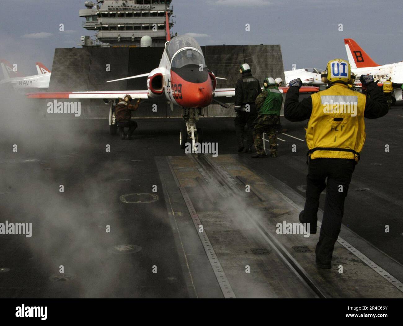 A deck edge operator and arresting gear officer ensure the flight deck is  clear for an incoming T-45C Goshawk training jet aboard the aircraft  carrier USS John F. Kennedy (CV 67). 