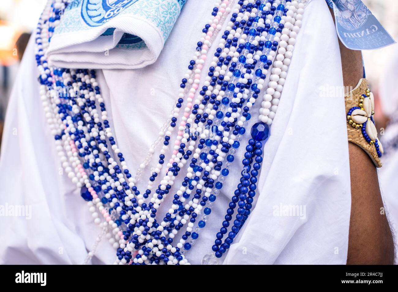 A set of beaded necklaces in shades of blue and white, suspended from a white robe for display Stock Photo