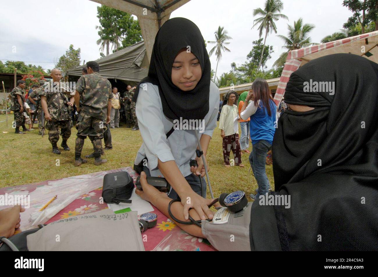 US Navy  A young Muslim volunteer checks a local Filipino woman's vital signs while participating in a Medical Civil Action Program (MEDCAP) located on Basilan Island. Stock Photo
