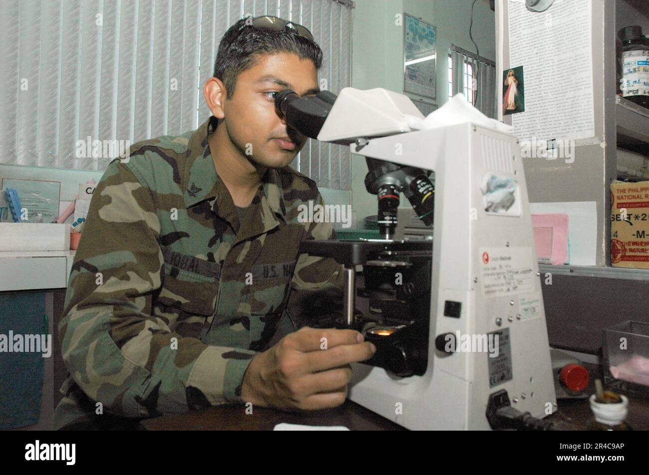 US Navy  U.S. Navy Hospital Corpsman 3rd Class examines blood chemistry using a microscope in the medical laboratory at the Zamboanga Medical Center. Stock Photo