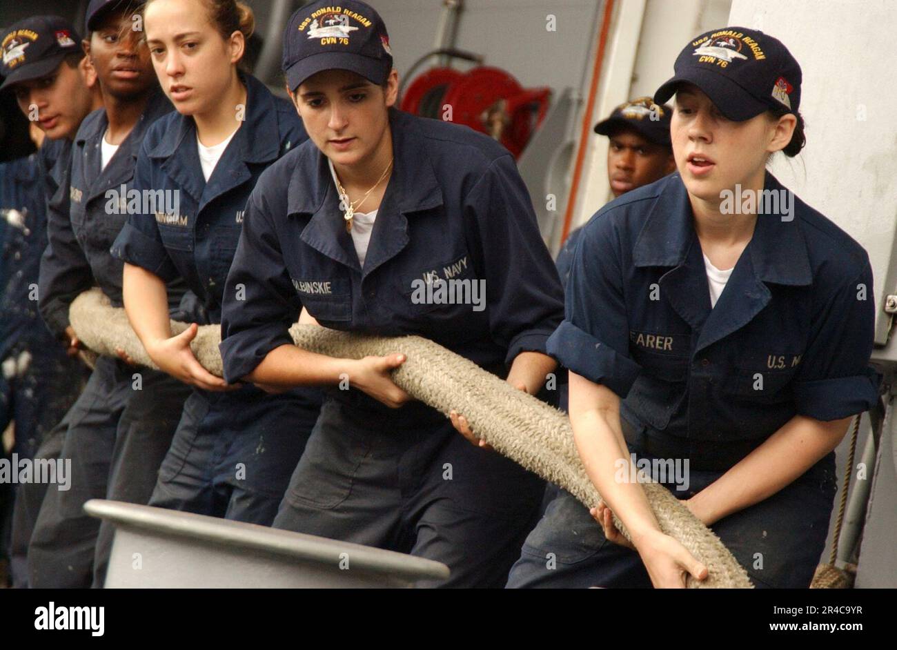 US Navy Seaman leads the heaving of a mooring line as USS Ronald Reagan ...