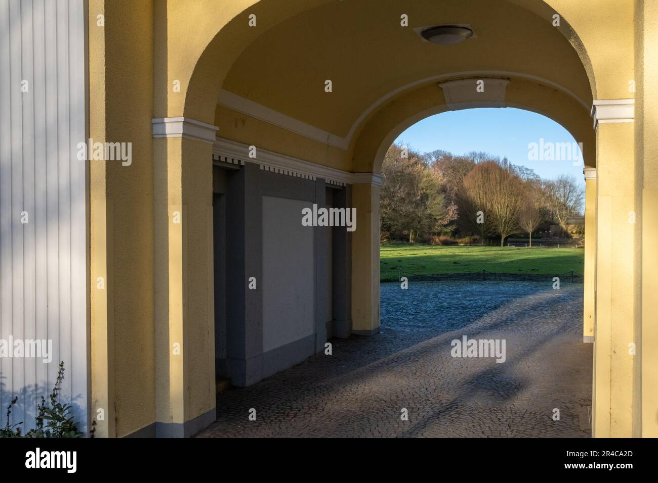 A scenic archway entrance surrounded by lush green grass and tall stone ...