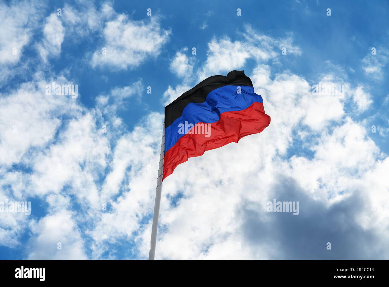 Flag of the self-proclaimed Donets People's Republic (DPR or DNR) is waving in front of blue sky and clouds Stock Photo