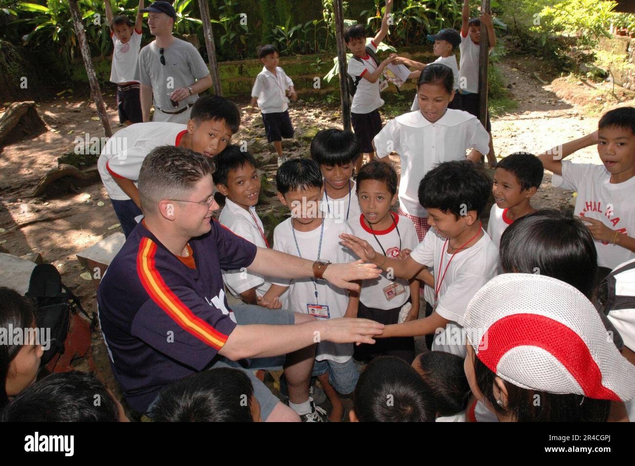 US Navy Boatswain's Mate 1st Class plays with the children of Gordon Heights II Elementary School, Olongapo City, Philippines Stock Photo