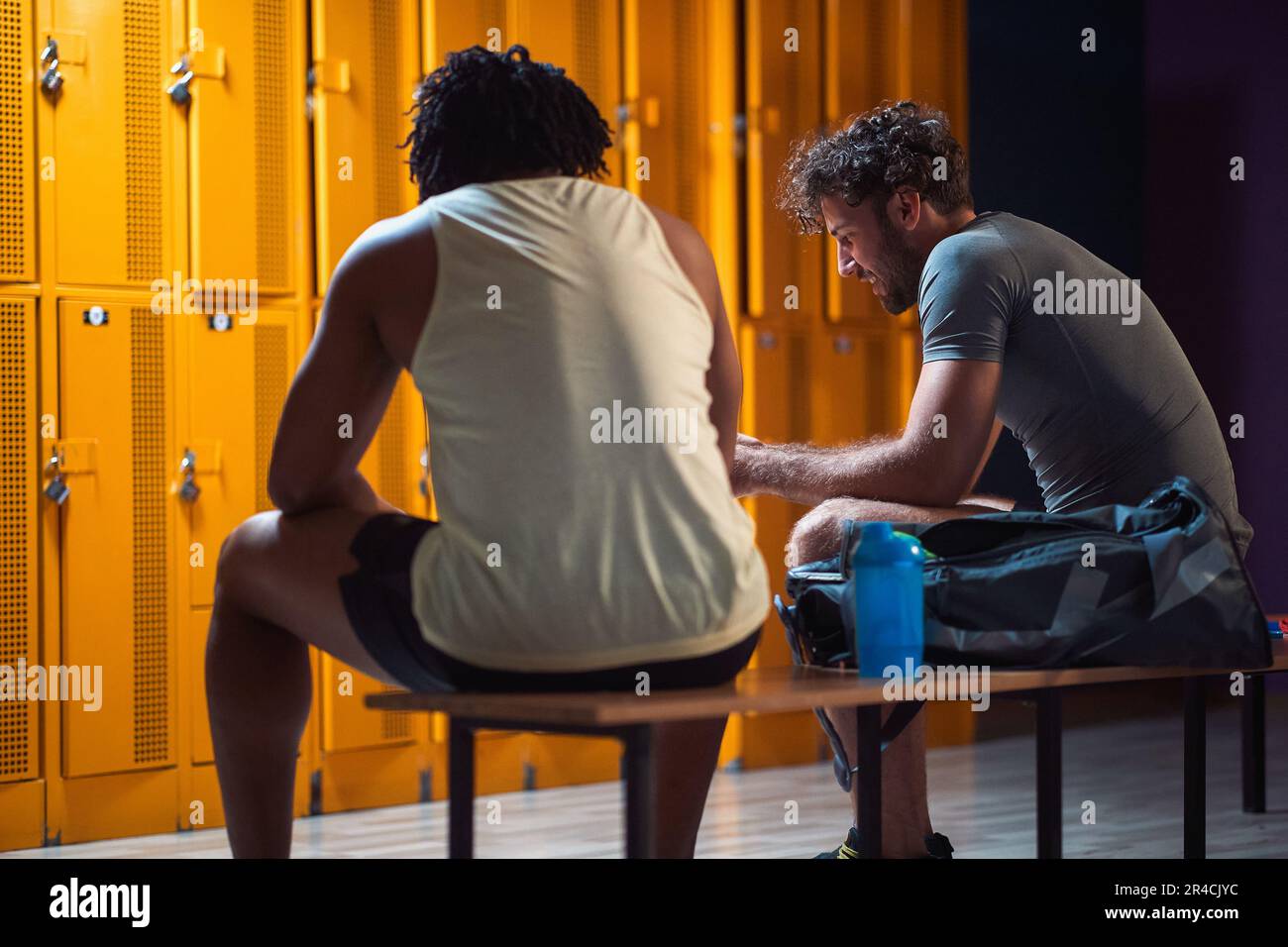 Two men in the locker room having a conversation after workout, enjoying each others company