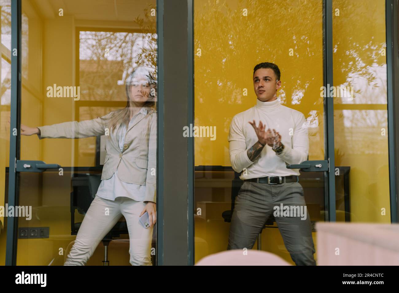 Two business colleagues goofing off in the phone booths at the office Stock Photo