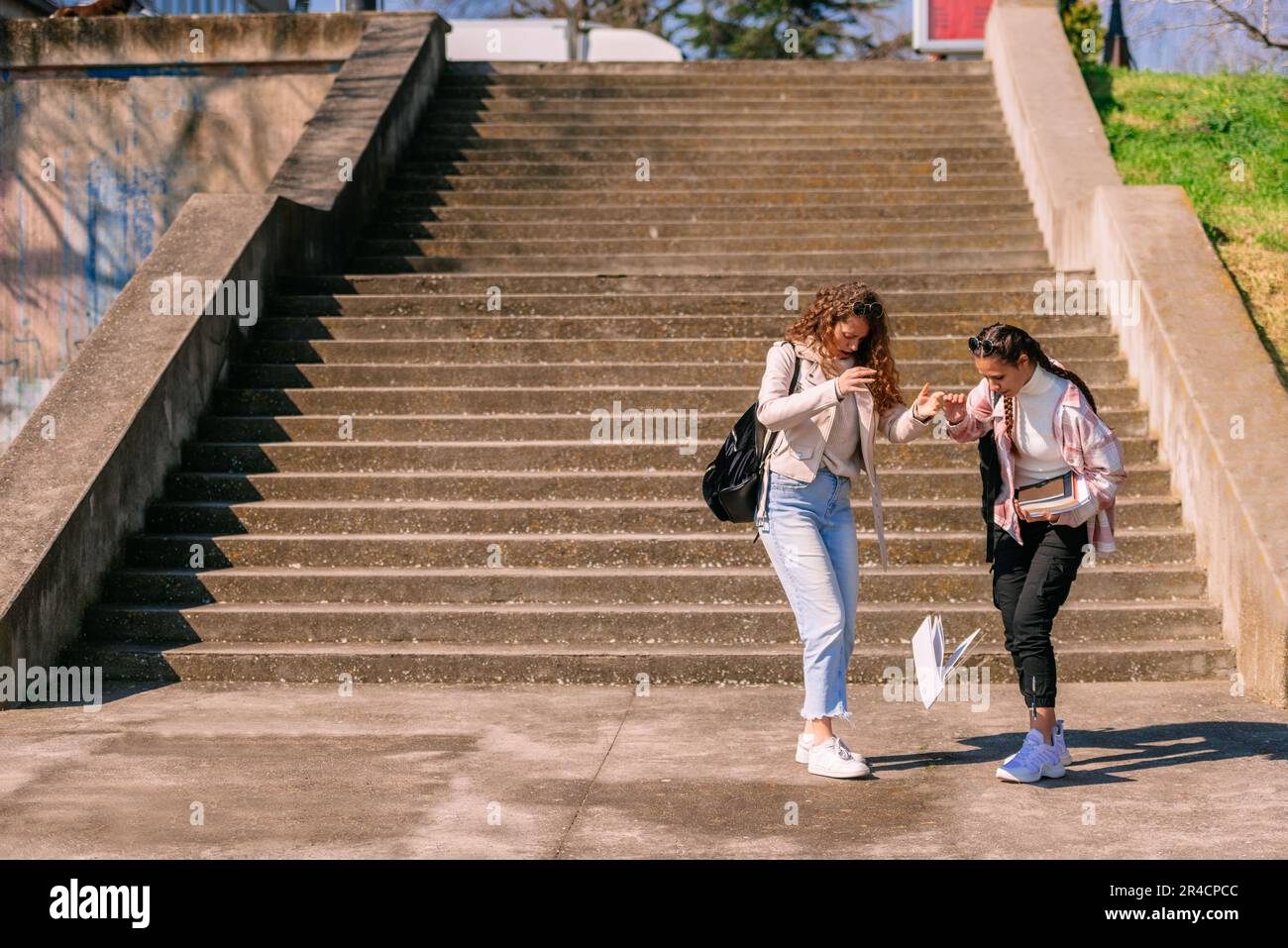 Curly haired girl dropped notebook. She thought the ground is wet ...