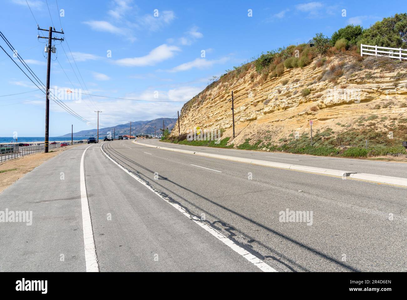 Curve along a coasal highway running at the foot of a cliff on a clear autumn day Stock Photo