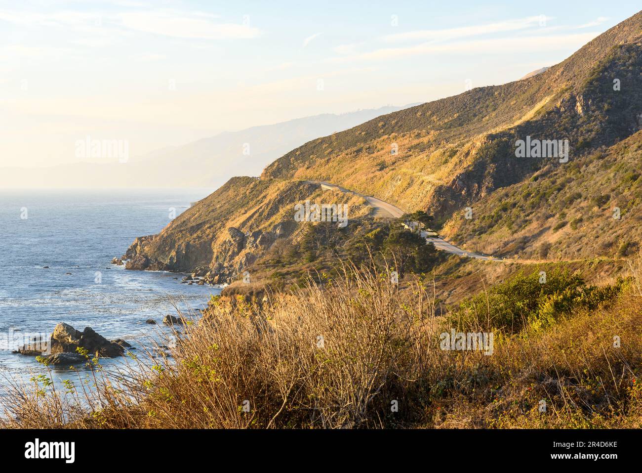 View of a the rugged coast of California partly shrouded in fog rolling over from the ocean at sunset in autumn Stock Photo