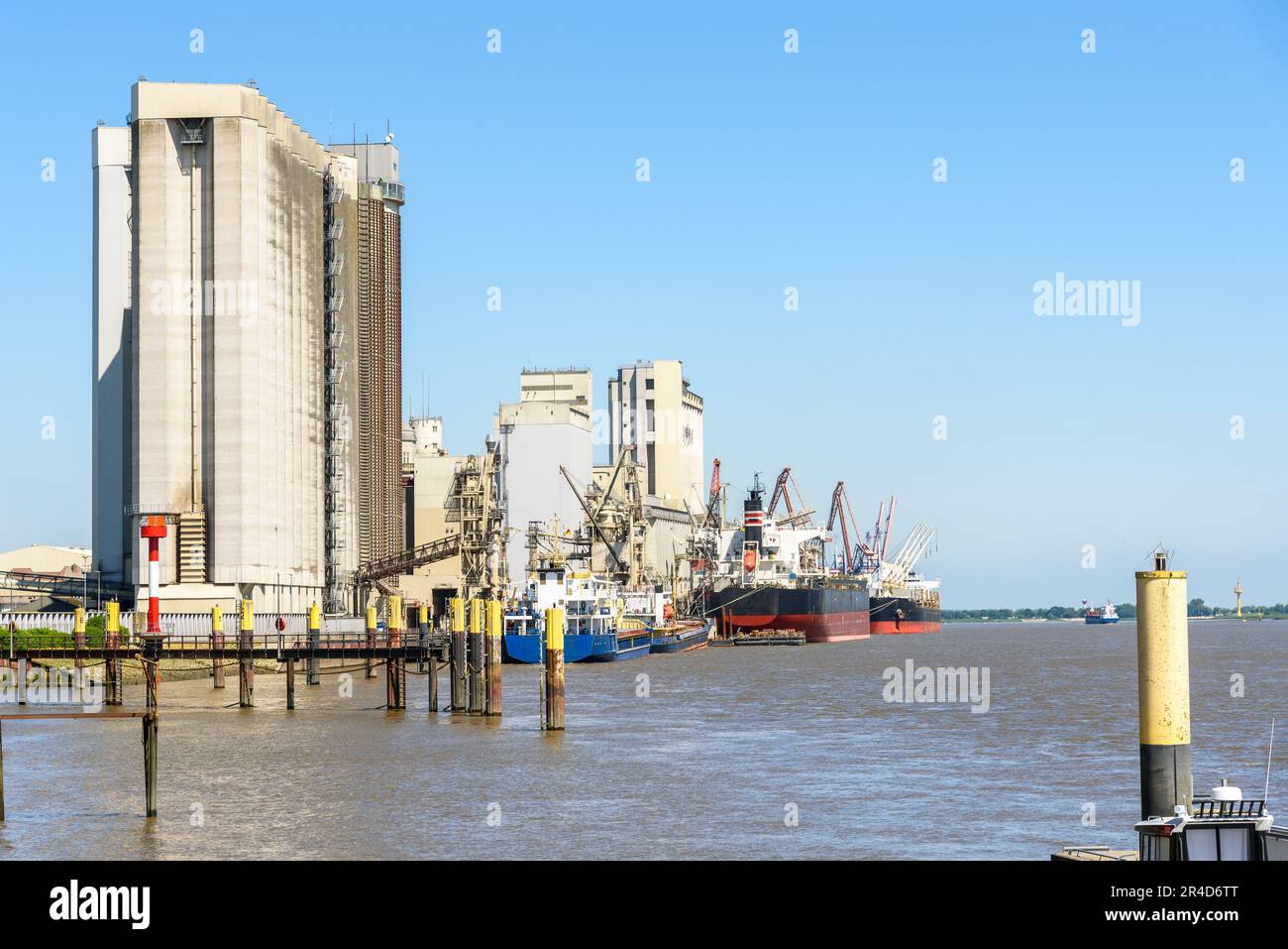 Bulk carrier ships moored to a commercial dock on a river harbour on a clear summer day Stock Photo
