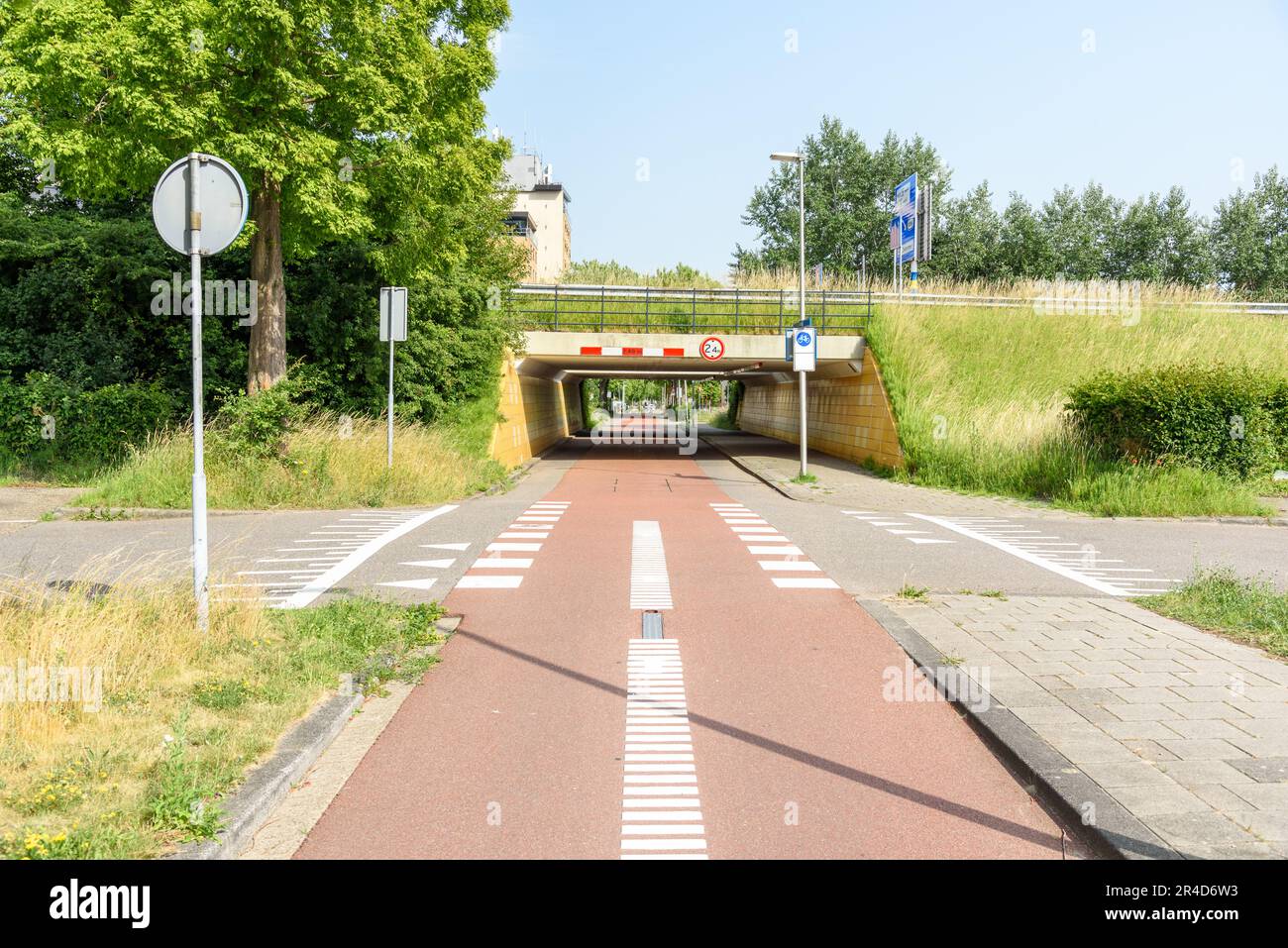 Deserted suburban bicycle path passing under a motorway on a sunny summer day Stock Photo