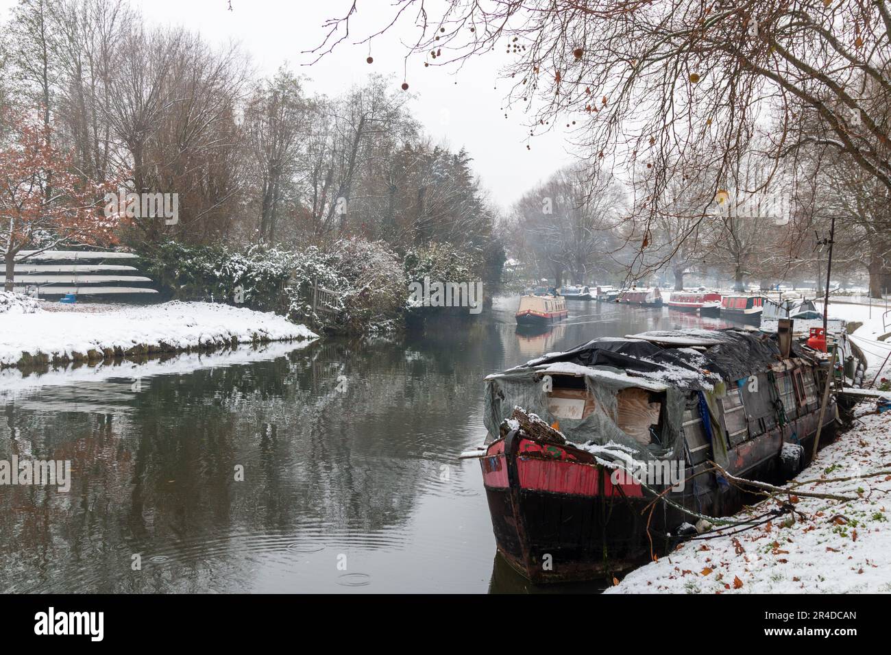 A narrowboat moored on the River Cam at Stourbridge Common, Cambridge, UK on a snowy, winter day. Stock Photo