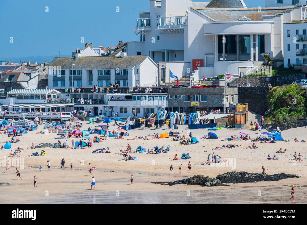St Ives, UK. 27th May, 2023. People flock to the beach, in front of the Tate St Ives, to sunbathe as well as take part in watersports and boat trips - Sunny weather for the bank holiday weekend in St Ives. Credit: Guy Bell/Alamy Live News Stock Photo