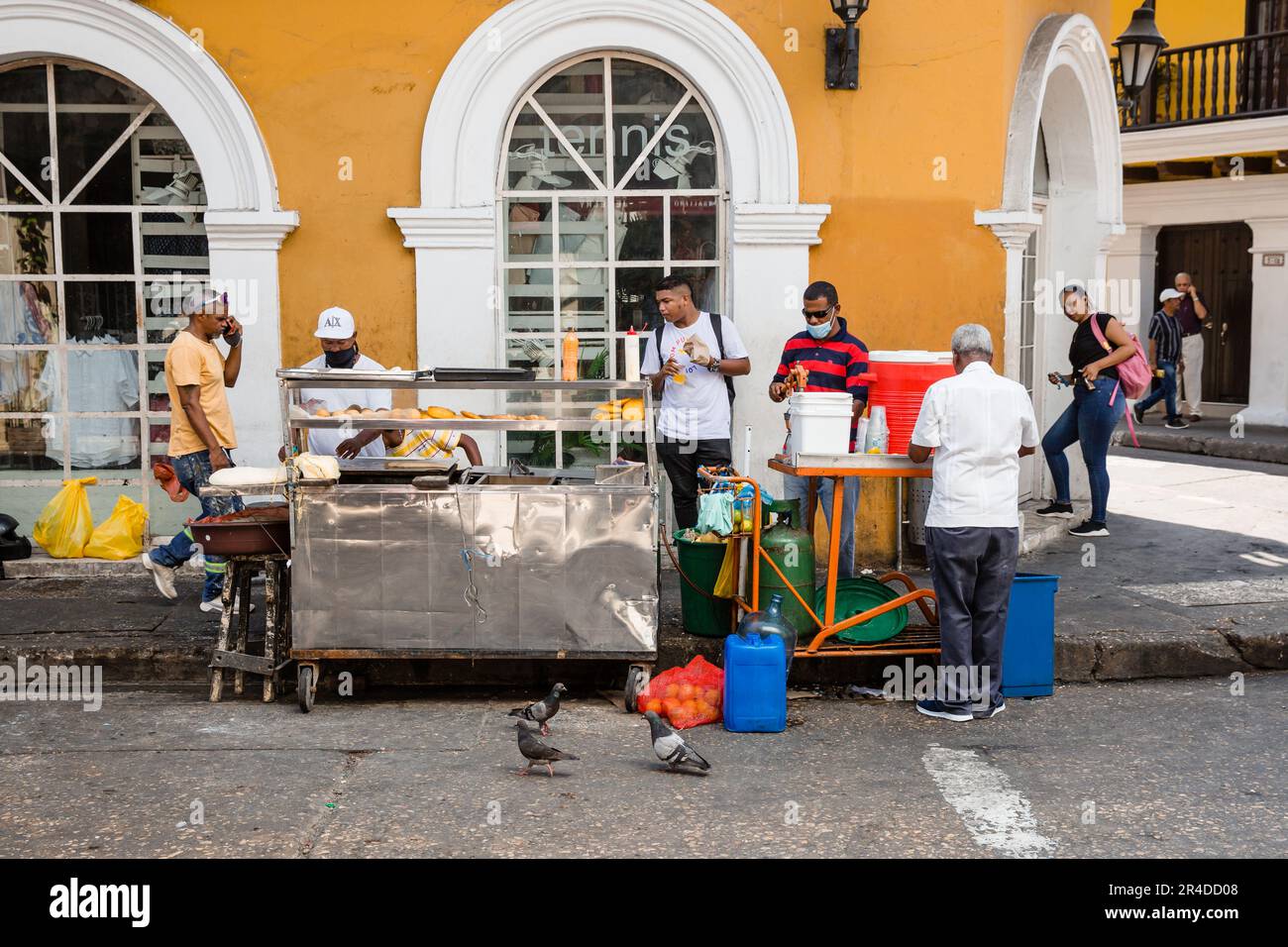 People gather near a street food cart in the old town of Cartagena Colombia Stock Photo