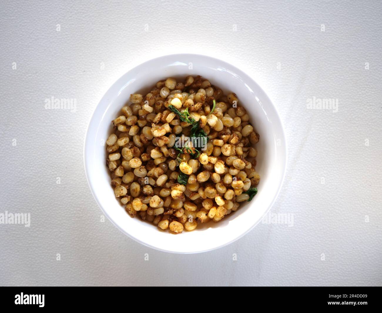 Jagung pulut or Corn pulut is a typical food from East Nusa Tenggara made from fried white corn mixed with salt and basil leaves. Stock Photo